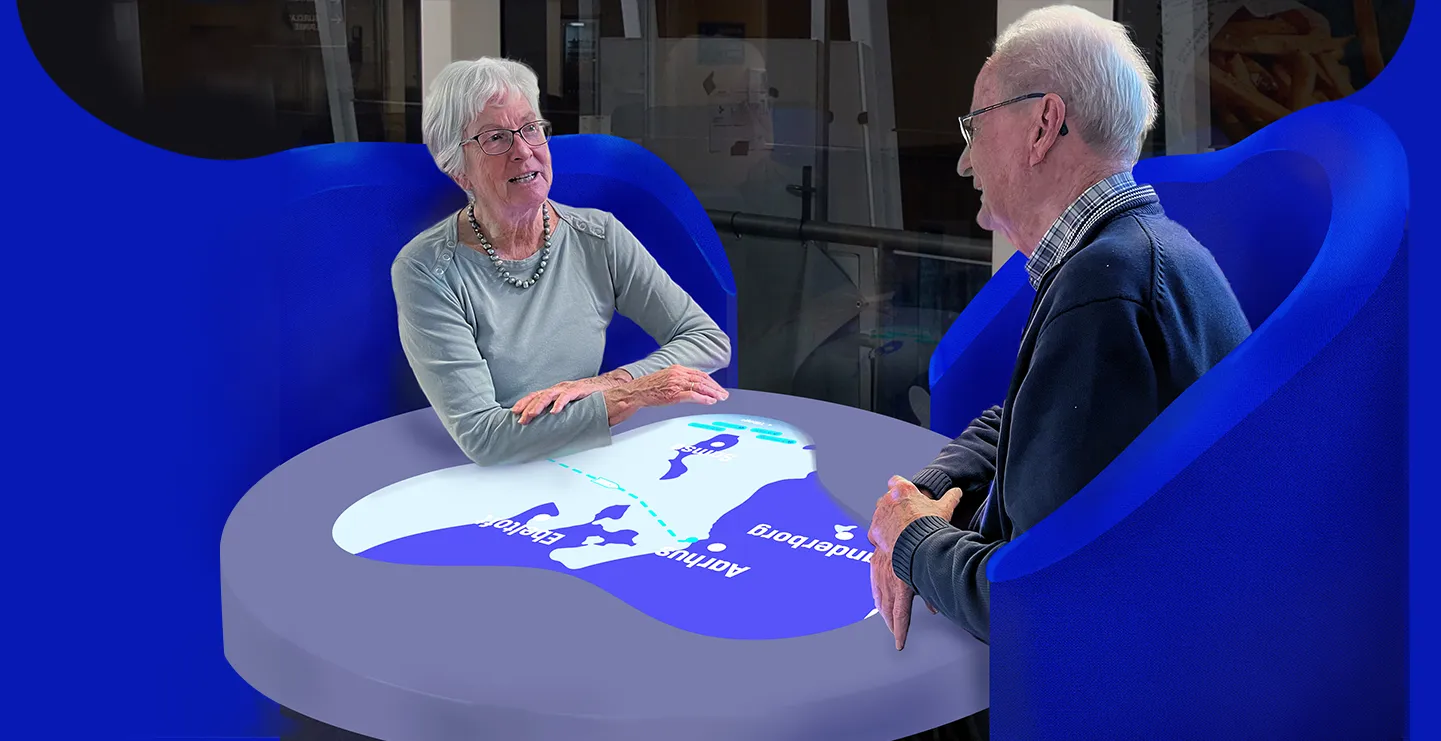 Two senior ferry passengers talking together while an interactive table is on
